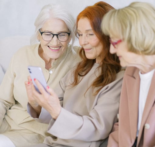 Three elder white women looking at the phone